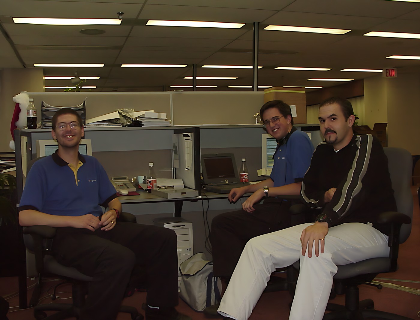 Three men sitting in an office cubicle